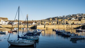 Un port avec des bateaux amarrés, un mur de pierre et des bâtiments en arrière-plan.
