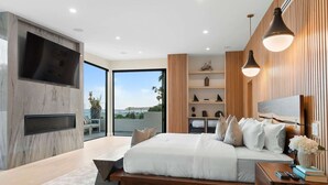 Une chambre moderne avec un grand lit, un téléviseur intégré et une vue sur l’extérieur.