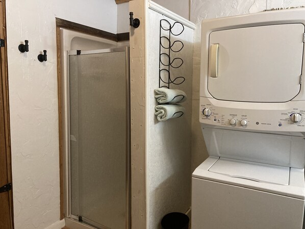 A laundry room with a washing machine, dryer, and a towel rack with towels.