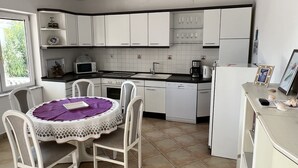 A compact kitchen with white cabinets, a dining table with a purple tablecloth, and a refrigerator. - Villa Irmica - Impressive pool, spacious apartment (86 m²) - first floor (Donja Jagodnja)