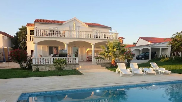 A two-story house with a swimming pool, lounge chairs, and a barbecue area. - Villa Irmica - Impressive pool, spacious apartment (86 m²) - first floor (Donja Jagodnja)