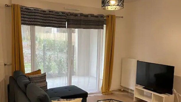 Un salon moderne avec un canapé, un téléviseur et une table basse en verre.