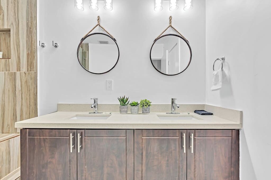 Une salle de bain avec deux lavabos, des meubles en bois et deux miroirs ronds.