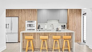 Una cucina moderna con un'isola centrale, elementi in legno e sgabelli da bar.