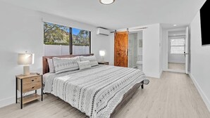 Una camera da letto con un letto, un comodino, una lampada, una finestra e una porta.