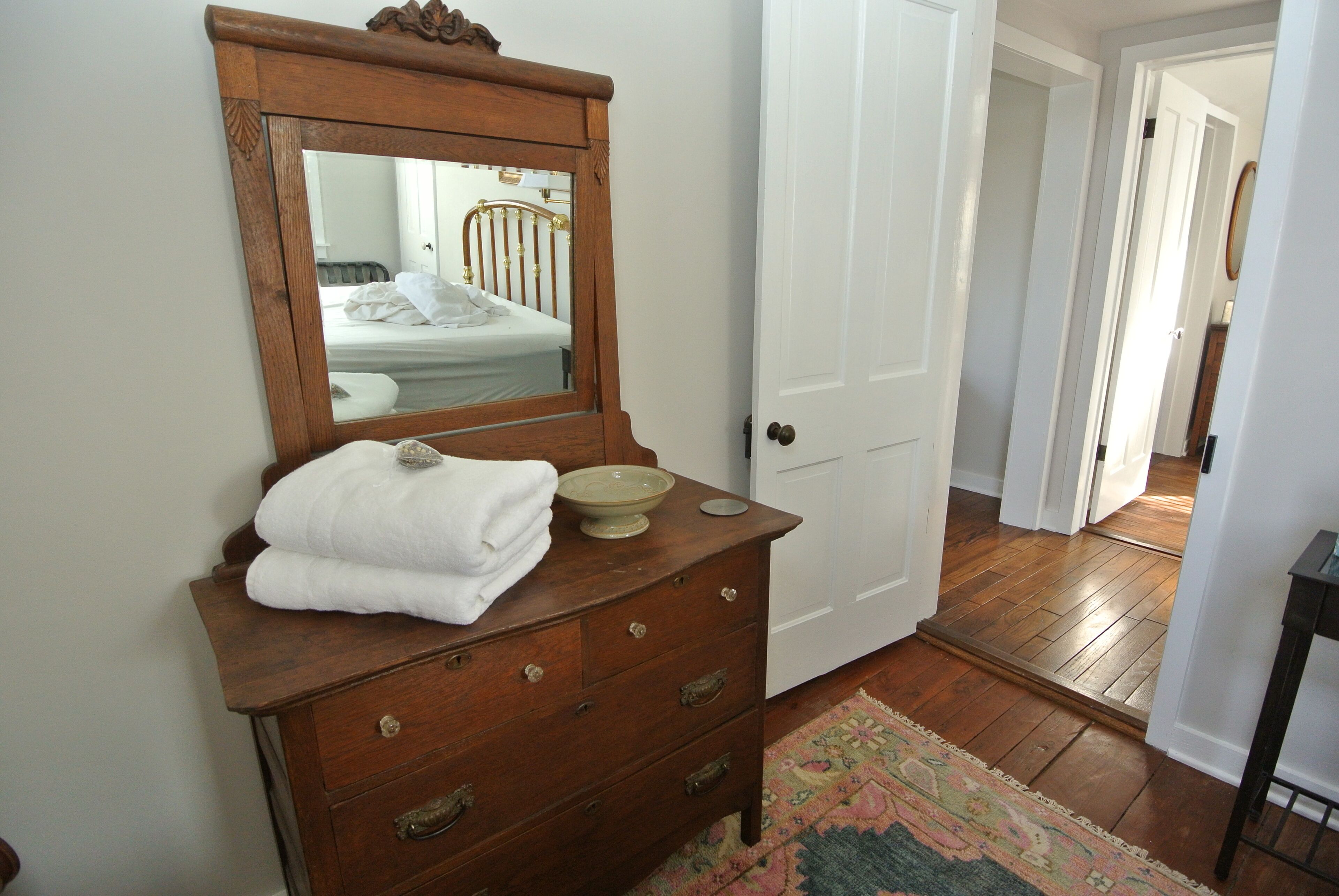 Une commode en bois avec un miroir, une serviette blanche et un bol.
