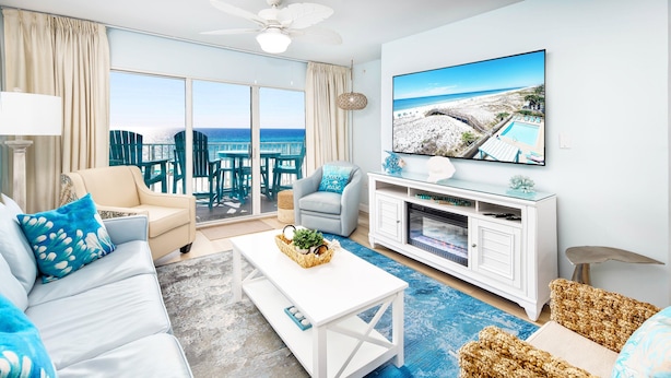 Uma sala de estar espaçosa com uma televisão grande, assentos confortáveis e vista para a praia.