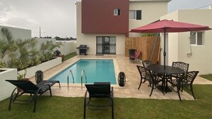Una casa moderna con piscina, mobiliario de exterior y zona de patio.