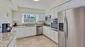 Eine moderne Küche mit weißen Schränken, Edelstahlgeräten, Granit Arbeitsplatten und einem eingebauten Backofen.