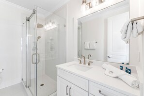 A modern bathroom with a glass-enclosed shower, a white vanity with a large mirror, and a towel rack. - Beach Views, Private Pool, Recently Remodeled - Steps to the Beach! (Santa Rosa Beach)