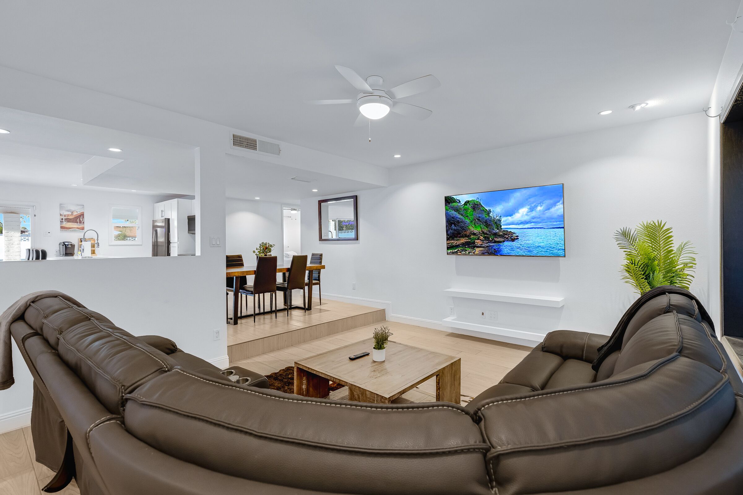 A modern living room with a brown leather sofa, a wooden coffee table, and a flat-screen TV mounted on the wall.