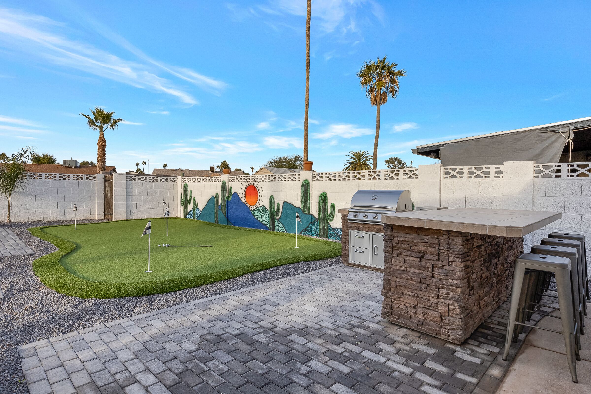Un giardino con un putting green, un'area barbecue e un camino in pietra.
