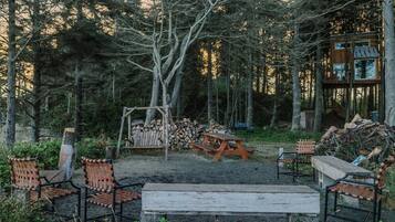 A rustic outdoor seating area with a swing, a picnic table, and a wooden bench.