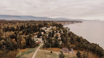Vue aérienne d’une zone résidentielle côtière, avec des maisons, une route et une étendue d’eau.