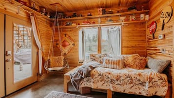 A cozy cabin interior with a bed, hanging chair, and a 'SLOW' sign on the wall.