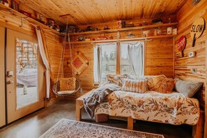 A cozy cabin interior with a bed, hanging chair, and a 'SLOW' sign on the wall.