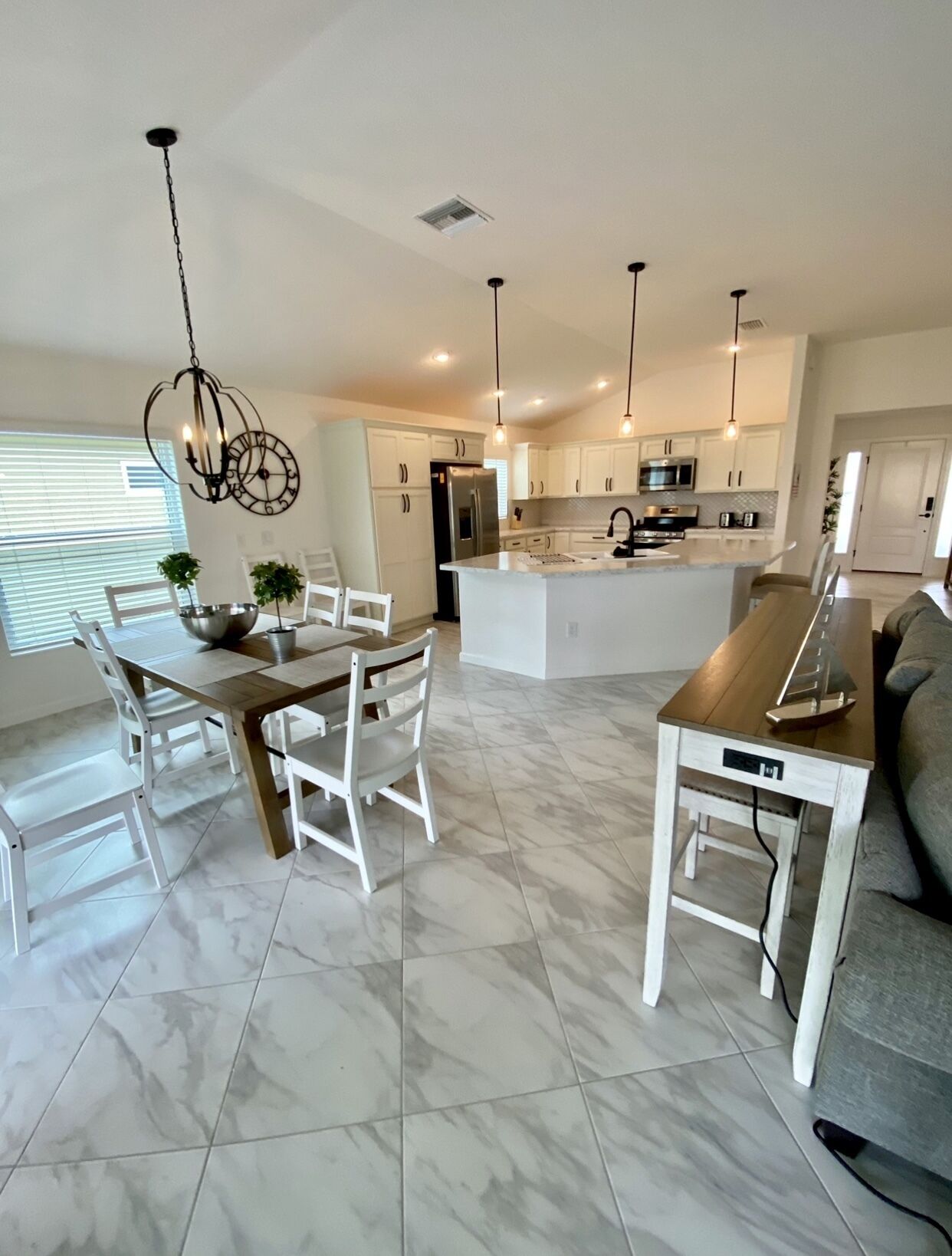 A modern kitchen with white cabinets, a central island, and pendant lighting.