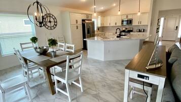A modern kitchen with white cabinets, a central island, and pendant lighting.