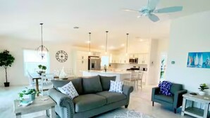 A modern living room with a sofa, a coffee table, and a dining area. - The Villages 3 bed/3 Kings, Private, Coastal decor, 1 min to Rec cntr & Pickleba (The Villages)