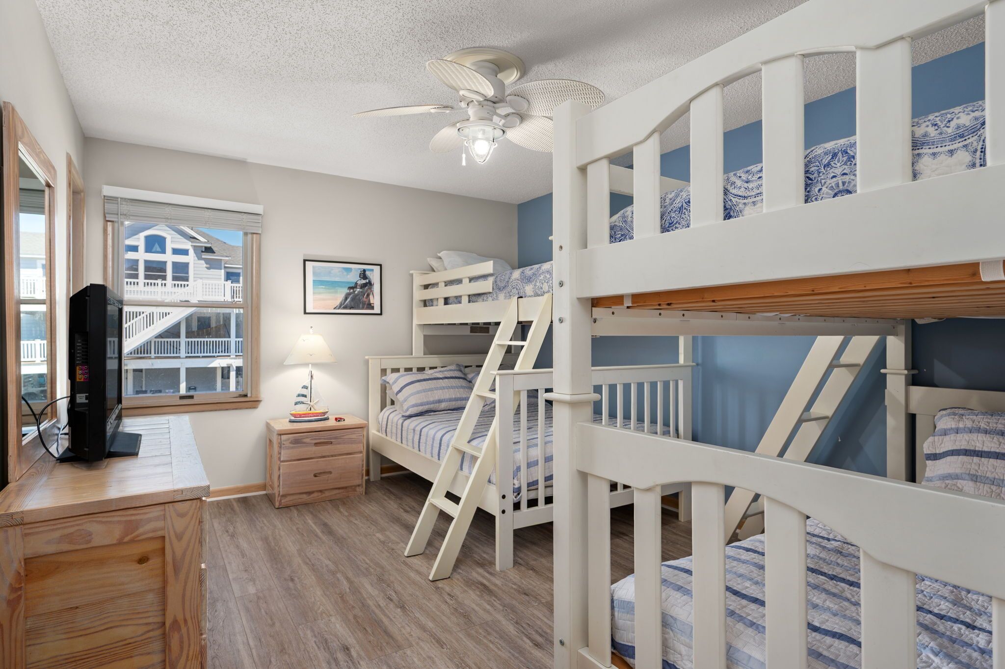 Une chambre pour enfant avec un lit superposé, un bureau et un téléviseur.