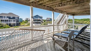 A wooden deck with a hammock, chairs, and a view of houses and greenery. - Oceanside, Lovely, New home! Sat-Sat (Corolla)
