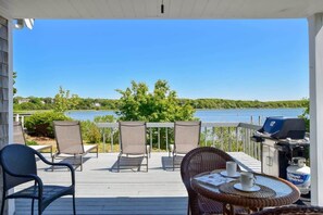 A deck with outdoor seating and a grill, overlooking a lake. - Waterfront with Private Dock! (Eastham)