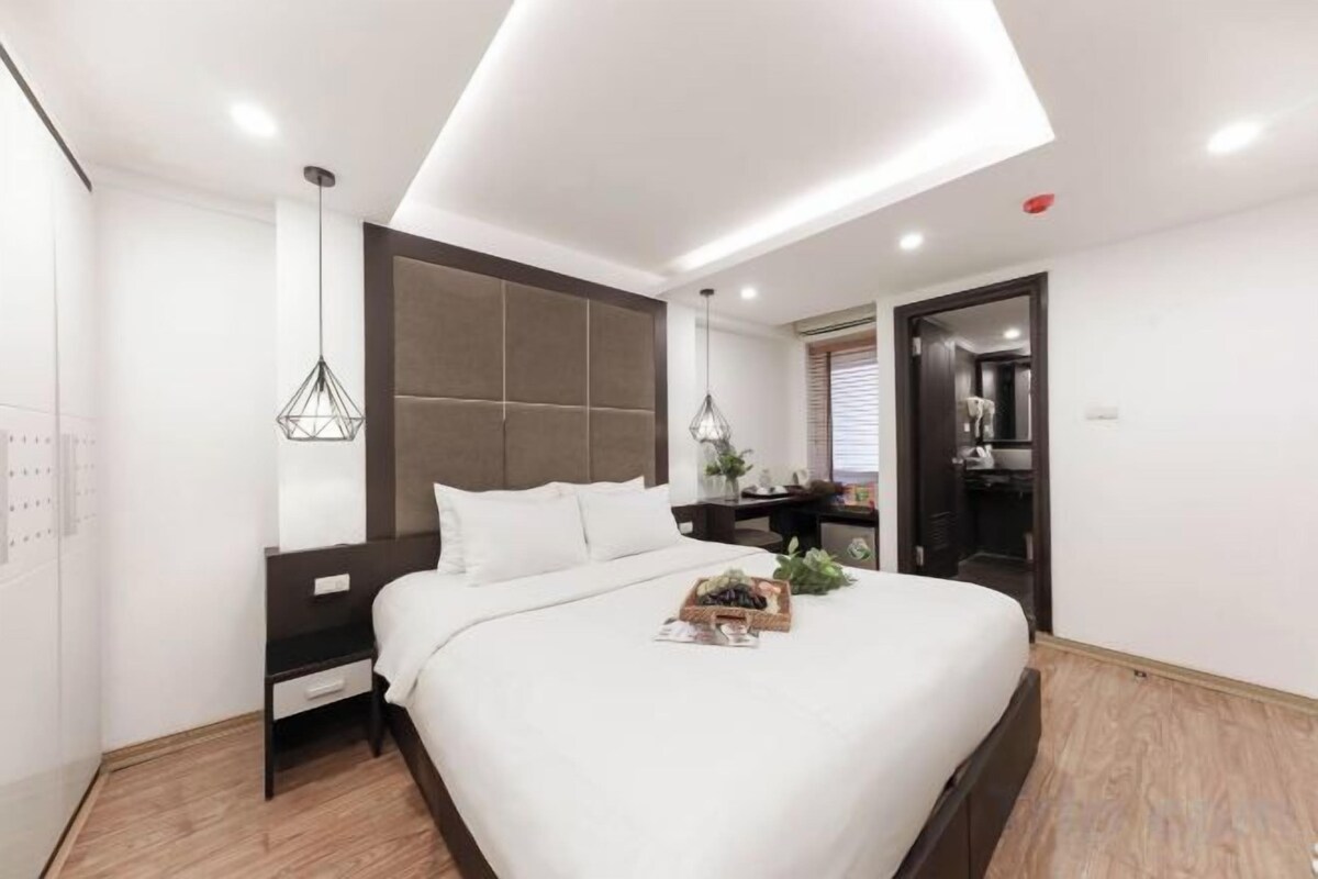 A modern bedroom with a large bed, bedside tables, a wardrobe, and a nightstand.