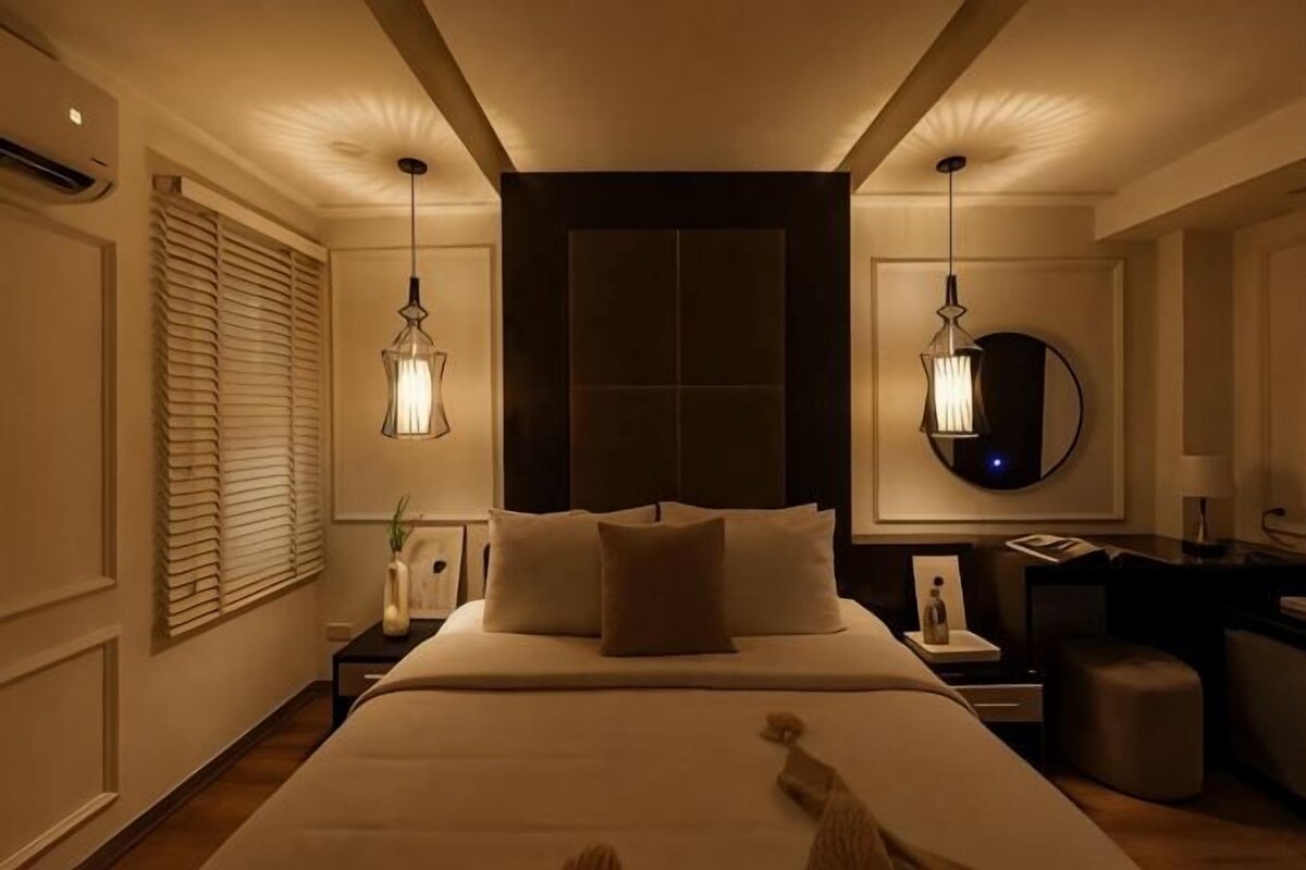 A hotel room with a large bed, bedside tables, a desk, and a mirror.