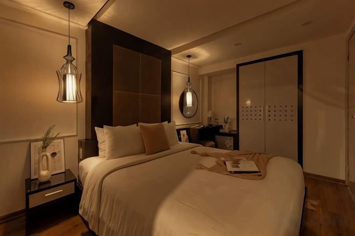 Een slaapkamer met een groot bed, nachtkastjes, een dressoir en een kledingkast.