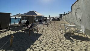 A beach with sun umbrellas, lounge chairs, and a concrete wall with a mural. - 9666llkhll (San Jose del Cabo)