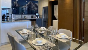 A modern dining area with a glass table, white chairs, and a contemporary chandelier. - 9666llkhll (San Jose del Cabo)