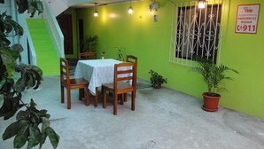 Un comedor con mesa y sillas, una escalera y una planta en maceta.