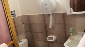 Un baño pequeño con inodoro, secamanos, dispensador de jabón y lavabo.