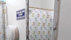 Un baño con lavamanos blanco, un espejo y una cortina de ducha con estampado de patos.
