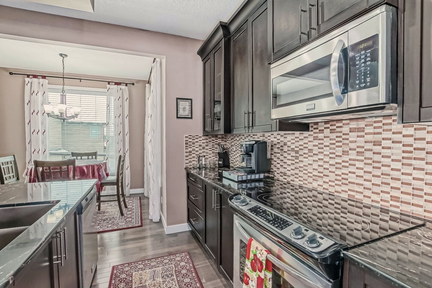 Una cocina moderna con armarios oscuros, un microondas, una estufa y un salpicadero de azulejos.
