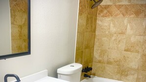 Un baño con lavamanos blanco, armarios de madera, inodoro y bañera.