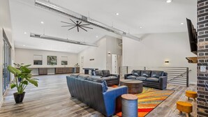 A spacious living area with a large sofa, a coffee table, and a rug. There is a potted plant and a small stool. - "The Spruce"-Gathering Tree is your Ultimate Family Reunion Spot (Flagstaff)