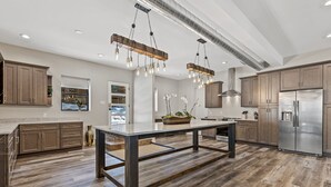A spacious kitchen with a central island, wooden cabinets, stainless steel appliances, and a modern pendant light fixture. - "The Spruce"-Gathering Tree is your Ultimate Family Reunion Spot (Flagstaff)