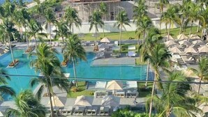 A resort pool area with palm trees, lounge chairs, and a wooden deck. - Luxurious Studio Playa Mujeres Cancun (Cancun)