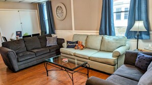Un salon avec deux canapés, une table basse et une horloge au mur.