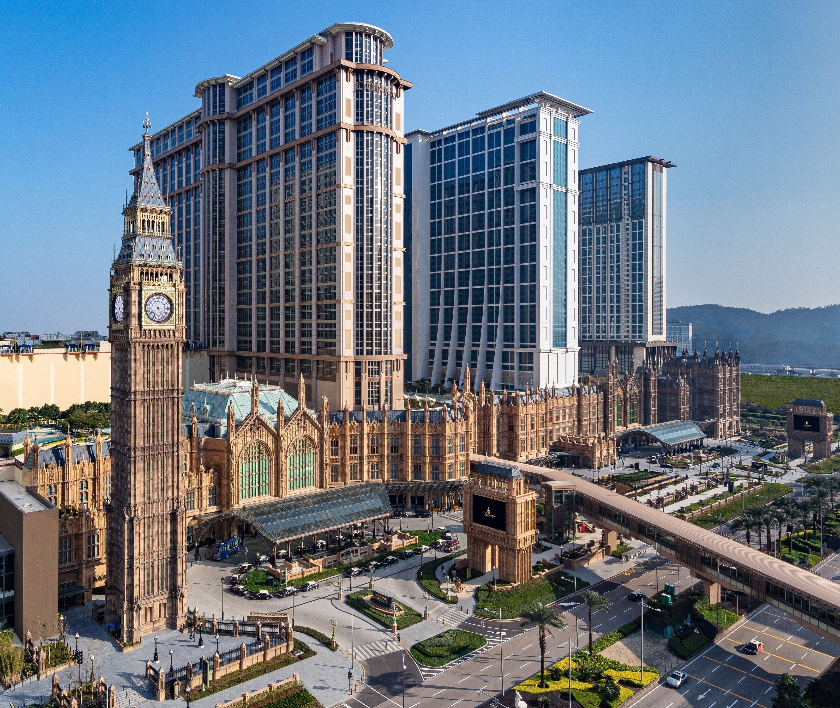 A large building with a clock tower, surrounded by modern high-rises.
