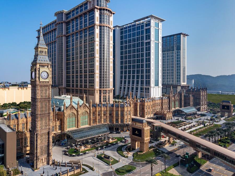 A large building with a clock tower, surrounded by modern high-rises.