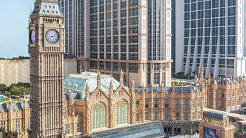Un edificio grande con una torre de reloj, rodeado de modernos rascacielos.