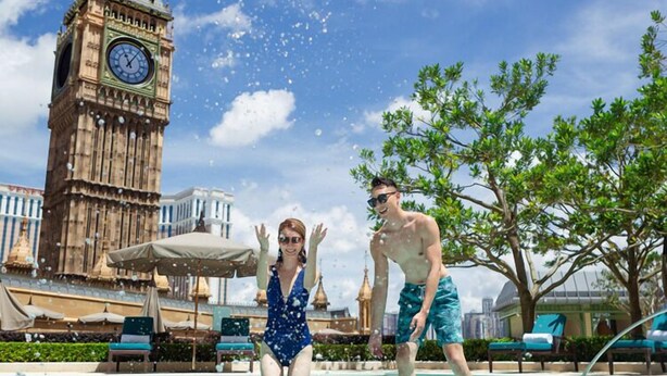 A swimming pool with a large clock tower in the background. - The Londoner Hotel (Cotai)