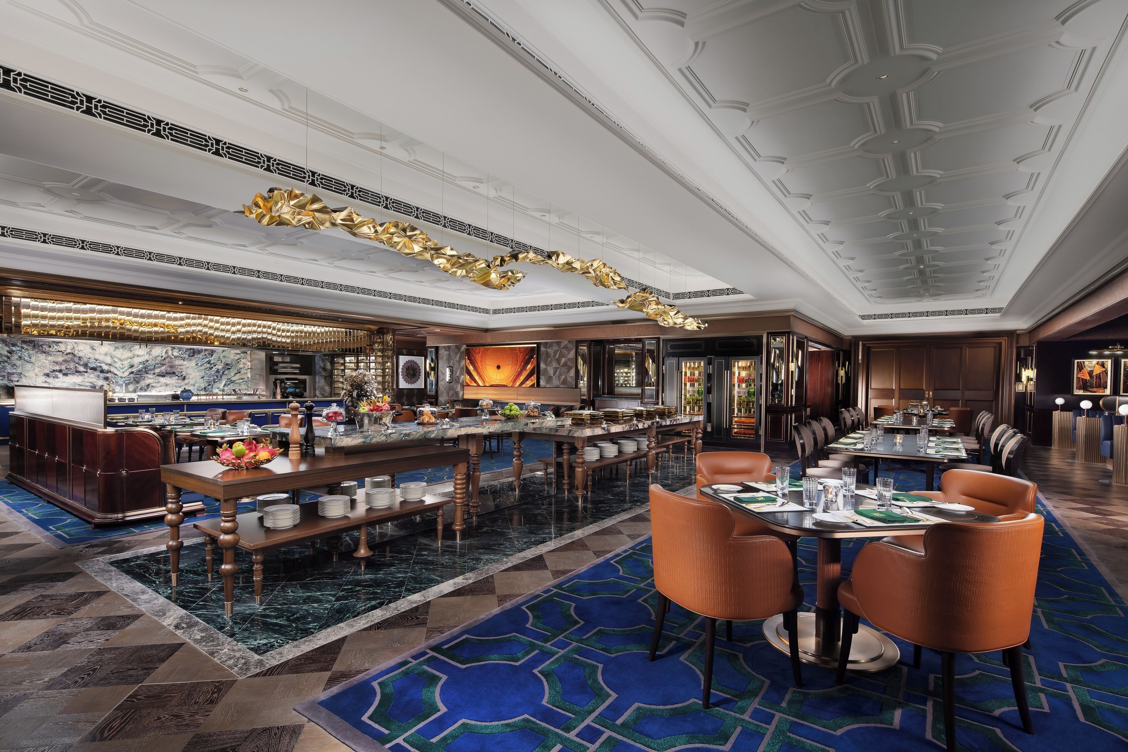 A luxurious hotel lobby with a marble reception desk, a bar area, and a dining section with tables and chairs.