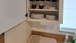 A kitchen with a built-in cabinet containing plates, bowls, and mugs.
