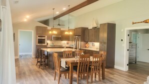 A spacious kitchen with modern appliances, a large island, and wooden chairs. - Waterfront Retreat (New Bern)