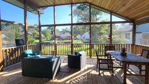 A covered outdoor deck with wicker furniture, a table, and chairs. - Waterfront Retreat (New Bern)