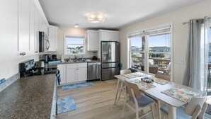 Una cocina moderna con armarios blancos, electrodomésticos de acero inoxidable y una zona de comedor con mesa y sillas.