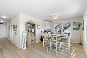 Un vaste espace de vie comprenant une table à manger, des chaises, une bibliothèque et un escalier menant à un autre niveau.